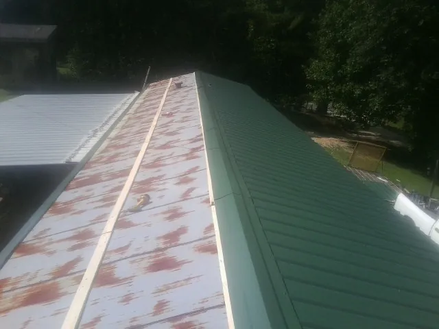 Old rusted panels beside newly installed green metal roofing — Wind Damage Roof Repair by Roofing Brothers in Cisco