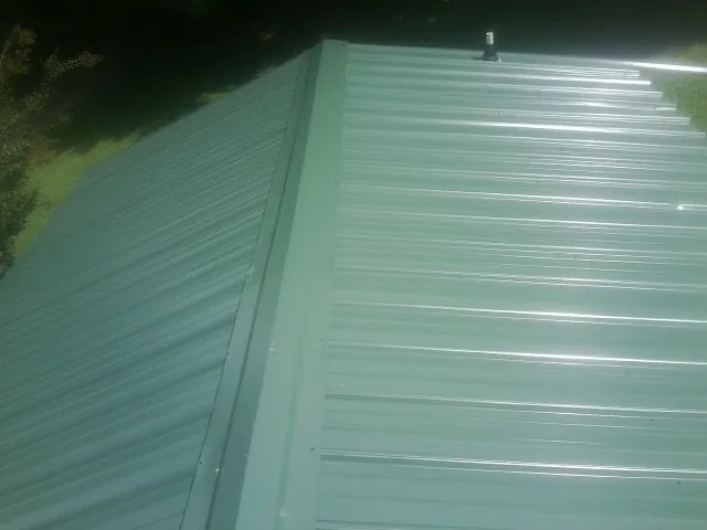 New green metal panels meeting at the ridge of a roof — Flat Roof Repair work by our crew in Cisco