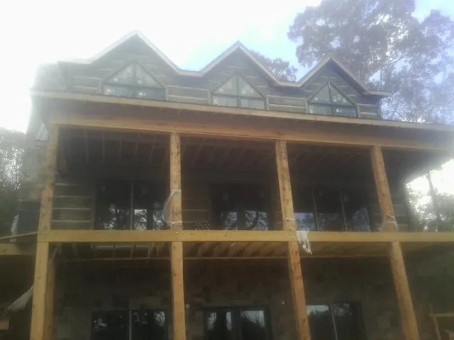 Dormers and porch framing on a large log home under construction — Roof Coating work by our crew in Cisco