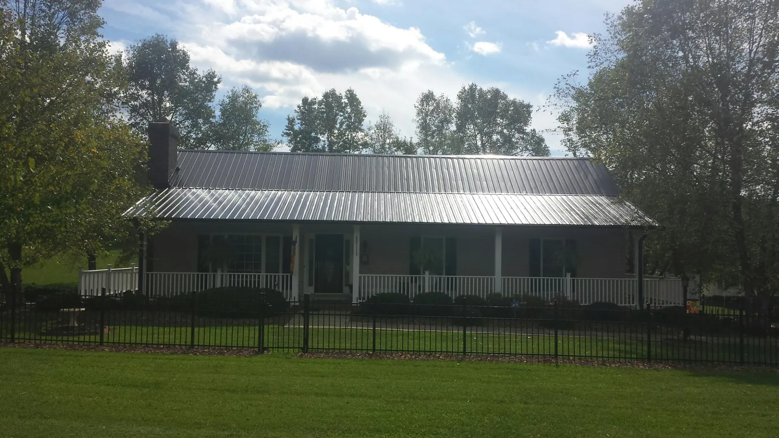 Gray metal roof on a brick ranch with a full width front porch — Gutter Guard Installation work by our crew in Cisco