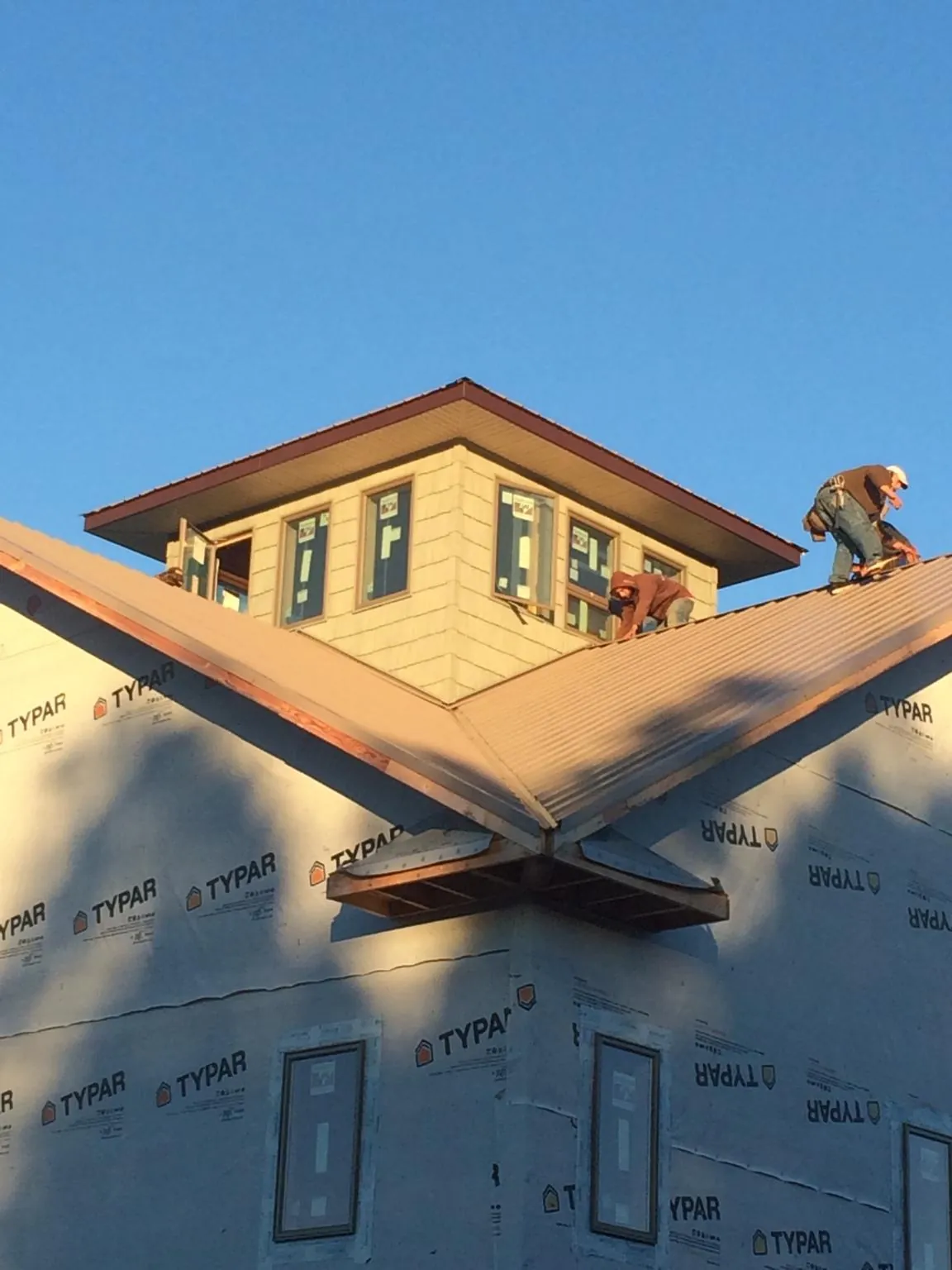 Roofers working around a rooftop cupola on a new metal roof at sunset — Roof Waterproofing in Cisco by Roofing Brothers